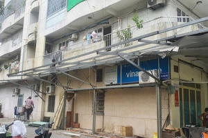 Người dân ở chung cư Độc Lập tự tháo dỡ phần mái che cơi nới sau vụ cháy khiến 8 người chết xảy ra hôm 6/7. (Ảnh: Phúc Uyên)