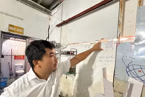 Ông Nguyễn Anh Sơn chỉ tay vào những vết nứt tường do công trình xây dựng kế bên gây ra. (Ảnh: Hà An)