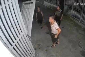 Bùi Hữu Khánh (áo sọc trắng) kéo sập cửa nhà hàng xóm vì bị phản ánh hát karaoke. (Ảnh cắt từ clip)