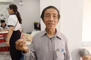 Ông Lương Văn Nông nhận quà tặng 200.000 đồng cho 2 vợ chồng ông từ điểm chi trả của UBND phường Bến Thành. Ảnh: Phúc Uyên.