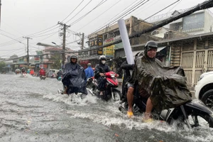 Đường Tô Ngọc Vân từ 16h trong cơn mưa nặng hạt đã biến thành "sông" khiến người dân vất vả di chuyển khi nước ngập quá nửa bánh xe.