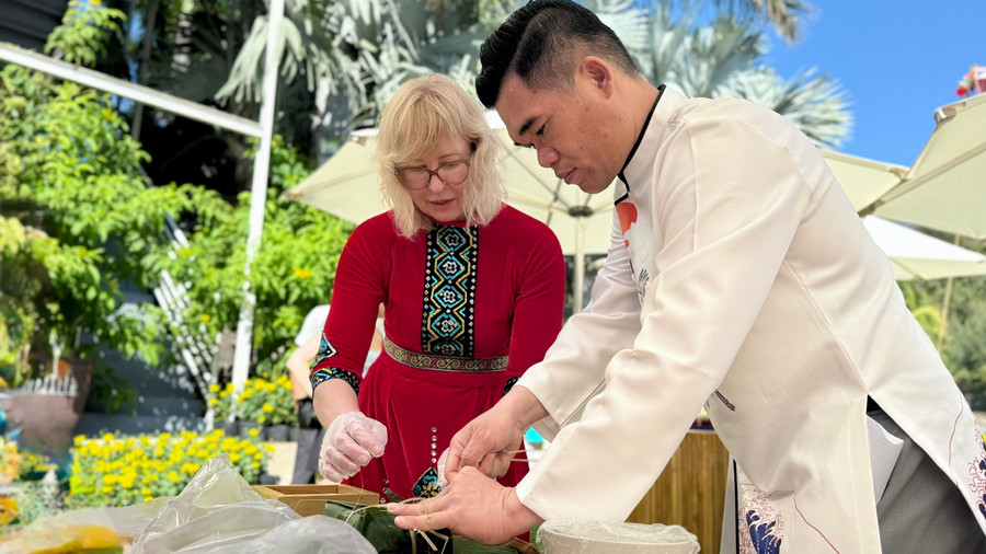 Du khách quốc tế trong trang phục truyền thống tham gia gói bánh chưng.
