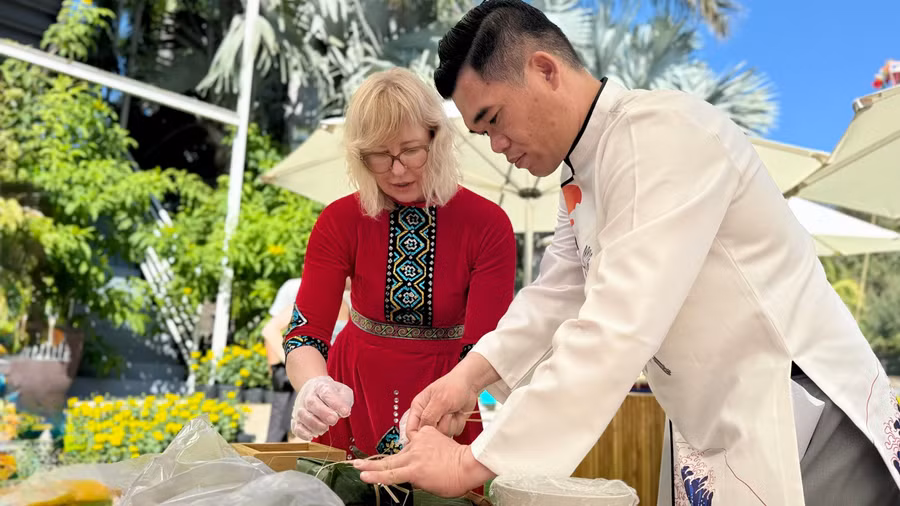 Du khách quốc tế trong trang phục truyền thống tham gia gói bánh chưng.