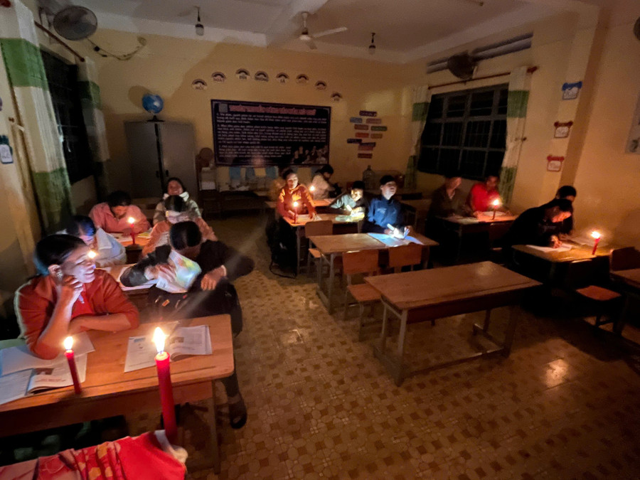 Các học viên của lớp xóa mù chữ học dưới ánh nến.