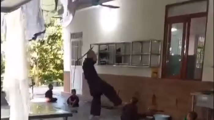 Người đàn ông đánh trẻ bằng roi. (Ảnh cắt từ clip)