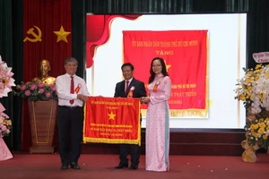 Ông Nguyễn Văn Hiếu - Giám đốc Sở GD&ĐT TPHCM trao cờ truyền thống của Uỷ ban Nhân dân TPHCM cho Trường Cán bộ Quản lý Giáo dục TPHCM. Ảnh: Thùy Linh. 