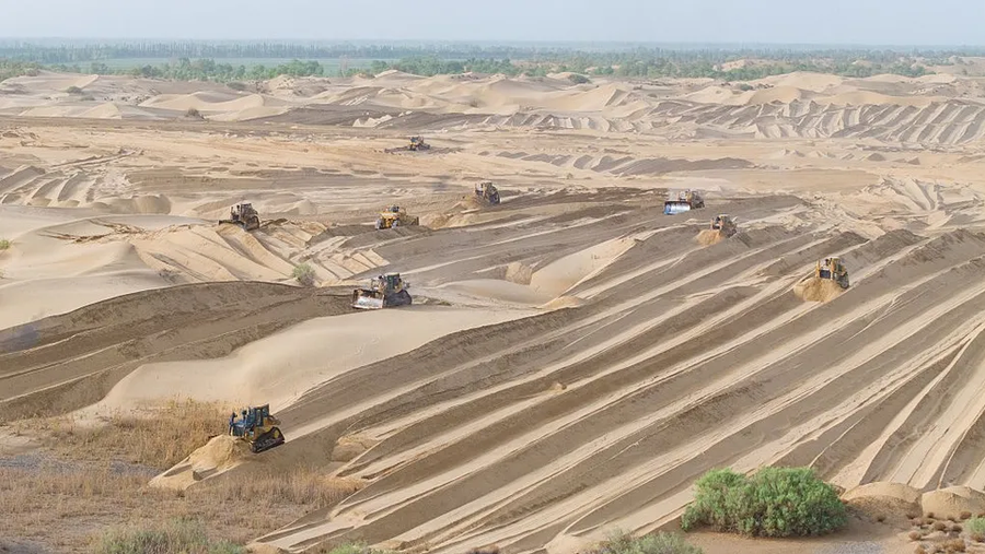 Máy móc hạng nặng được sử dụng để san bằng các cồn cát, nơi Trung Quốc muốn trồng cây và bụi cây dọc theo rìa sa mạc Taklamakan. 