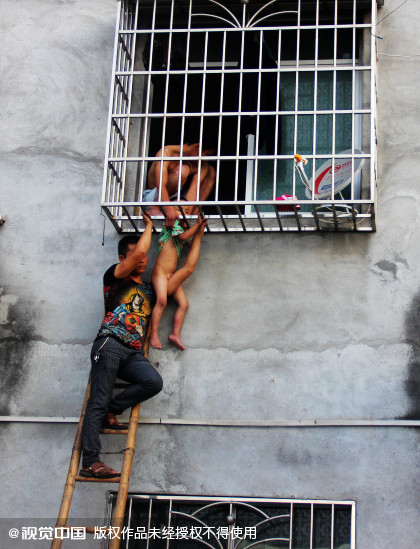 Hàng xóm phải đỡ bé trai để tránh cho em khỏi bị nghẹt thở. Ảnh: News Sina. be-trai-ket-dau-vao-chuong-cop-chung-cu-khi-o-nha-mot-minh