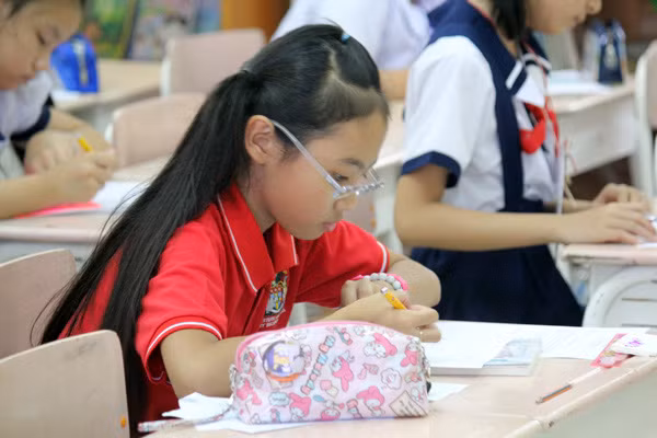 Khi vào phòng thi, cô bé tập trung viết rất nghiêm túc.