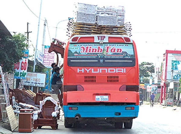 Một xe khách biển số Lào đang chất hàng lên nóc xe. Ảnh: Văn Thanh
