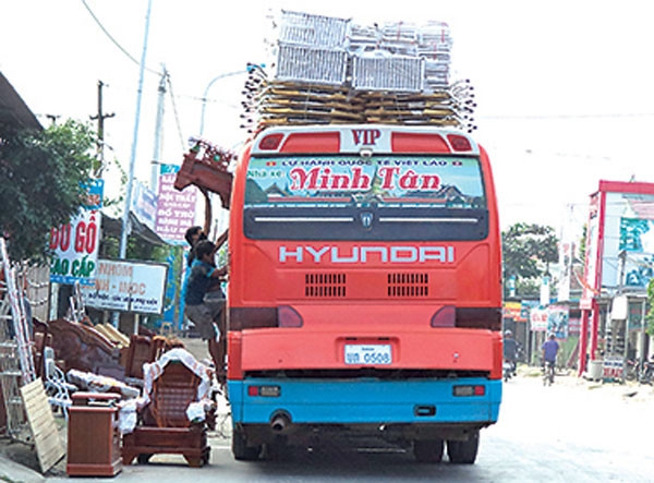 Một xe khách biển số Lào đang chất hàng lên nóc xe. Ảnh: Văn Thanh