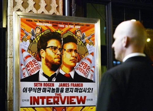 Nhân viên an ninh đứng đối diện poster quảng bá The Interview trước một rạp chiếu.