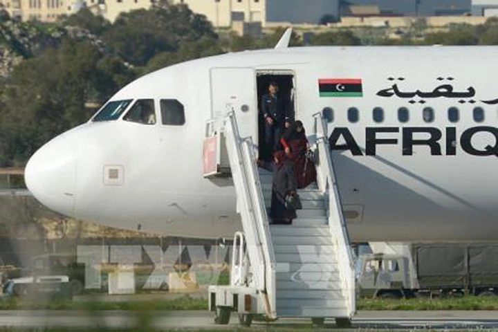 Các hành khách rời khỏi máy bay sau khi bị khống chế tại Valletta (Malta) ngày 23/12. AFP/TTXVN