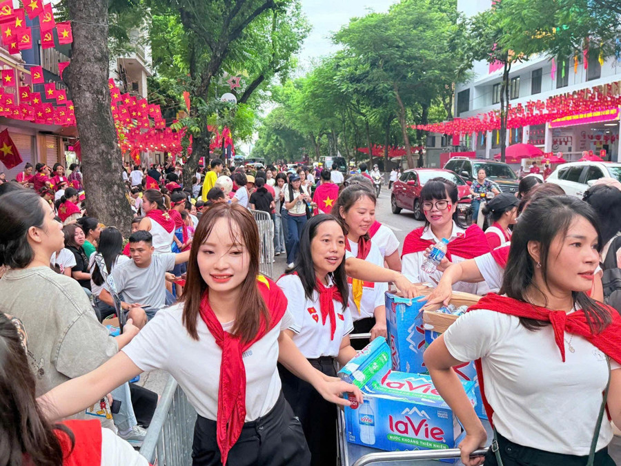 Các cô giáo kéo xe nước phát cho người dân đứng hai bên đường Nguyễn Thái Học chờ xem tổng duyệt A80. ly-11.jpg