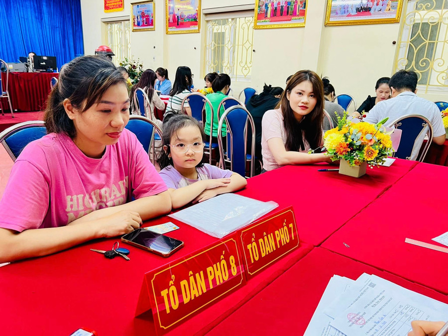 Phụ huynh đưa con tới trường để nhờ cán bộ giáo viên hướng dẫn đăng ký tuyển sinh trực tuyến vào lớp 1.
