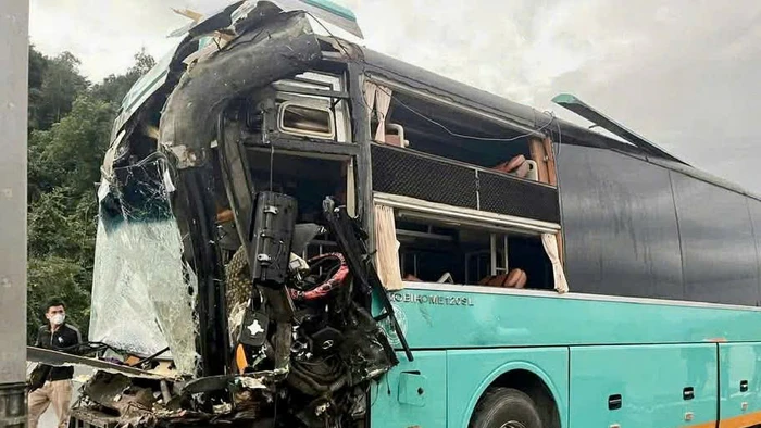 Phần đầu xe khách 50H-302.xx bị hư hỏng nặng sau cú va chạm, nhiều mảnh vỡ kính lái rơi vãi trên mặt đường.