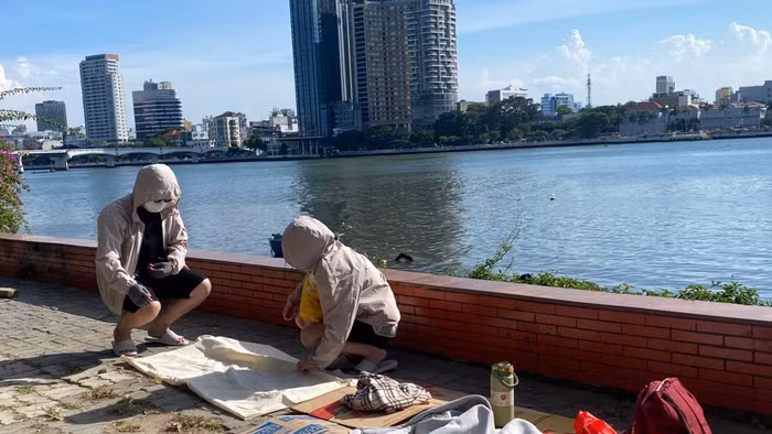Bìa carton, áo khoác và những vật dụng cá nhân được chuẩn bị sẵn bên sông Hàn cho hành trình chờ đợi xem khai mạc DIFF 2026. 