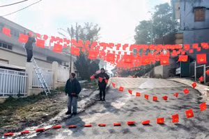 Cán bộ xã Tả Củ Tỷ treo cờ dọc con đường tại trung tâm xã.