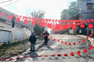 Cán bộ xã Tả Củ Tỷ treo cờ dọc con đường tại trung tâm xã.