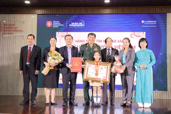 Anh hùng Phạm Tuân cùng đại diện lãnh đạo Tổ chức Kỷ lục Việt Nam và Hiệu trưởng Hệ thống VAS trao bằng Kỷ lục đến em Thư Hà. Ảnh: VietKings.