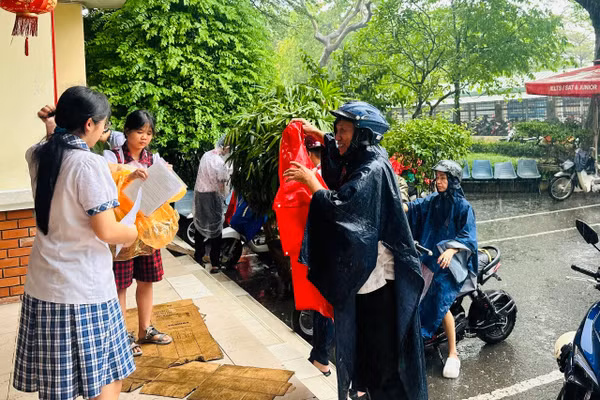 Phụ huynh đội mưa đưa con đến điểm thi Trường THCS Đặng Tấn Tài.