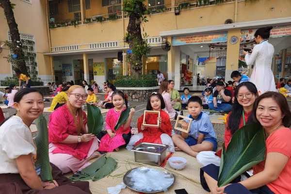 Học sinh, giáo viên và phụ huynh Trường Tiểu học Trần Hưng Đạo cùng nhau gói những chiếc bánh chưng xanh trong ngày hội "Gói Tết-Trao Xuân".