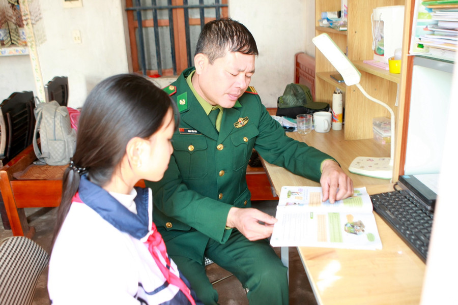 Trung tá Phan Văn Lâm, Chính trị viên phó Đồn Biên phòng Trà Lý hướng dẫn em Tạ Thị Mai Oanh học bài.