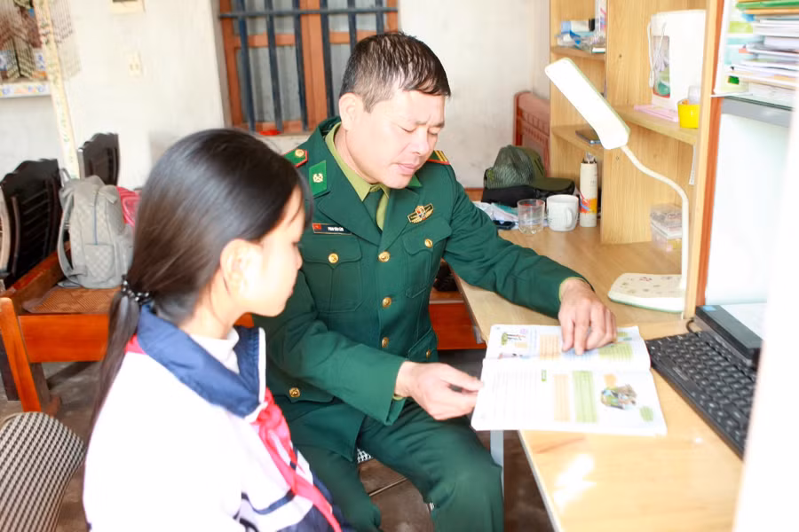 Trung tá Phan Văn Lâm, Chính trị viên phó Đồn Biên phòng Trà Lý hướng dẫn em Tạ Thị Mai Oanh học bài.
