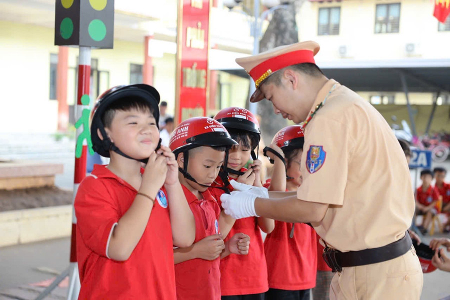 Các em học sinh được hướng dẫn sử dụng mũ bảo hiểm. 1000010788.jpg
