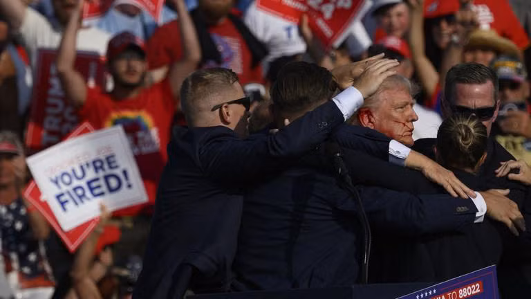 Ông Trump được nhân viên mật vụ bao quanh sau khi có tiếng súng vang lên tại một cuộc vận động tranh cử ở Butler, Pennsylvania. Ảnh: AFP / Jeff Swensen