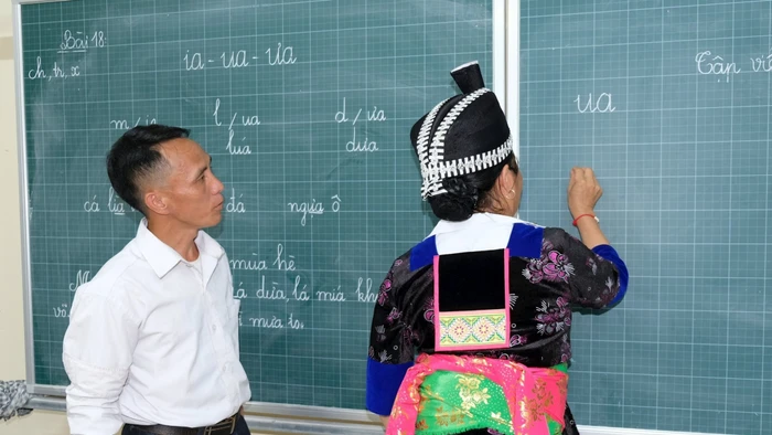 Thầy giáo Lỳ Bá Của (giáo viên Trường Phổ thông DTBT Tiểu học Hữu Khuông, Nghệ An) dạy học xóa mù chữ cho người dân. Ảnh: Hồ Lài