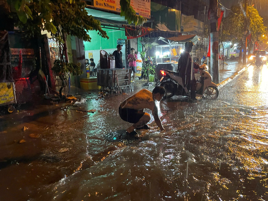 Người dân vớt rác ở nắp cống giúp nước thoát nhanh hơn. 49117abed5dd5d8304cc.jpg