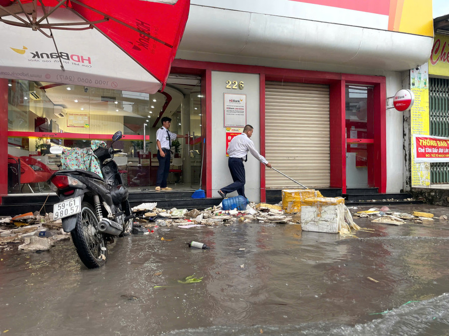 Ngập khiến rác từ nhiều nơi dồn ứ tại một ngân hàng khiến bảo vệ vất vả dọn dẹp. ngap-thu-duc-3.jpg