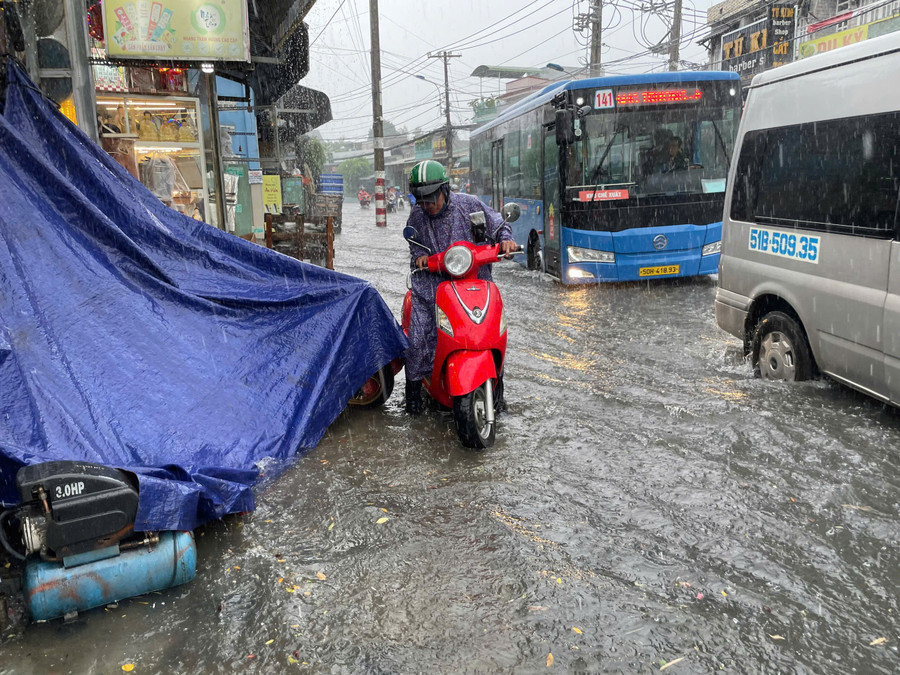 Một người dân cố gắng leo lên vỉa hè để vượt qua đoạn ngập. ngap-thu-duc-7.jpg