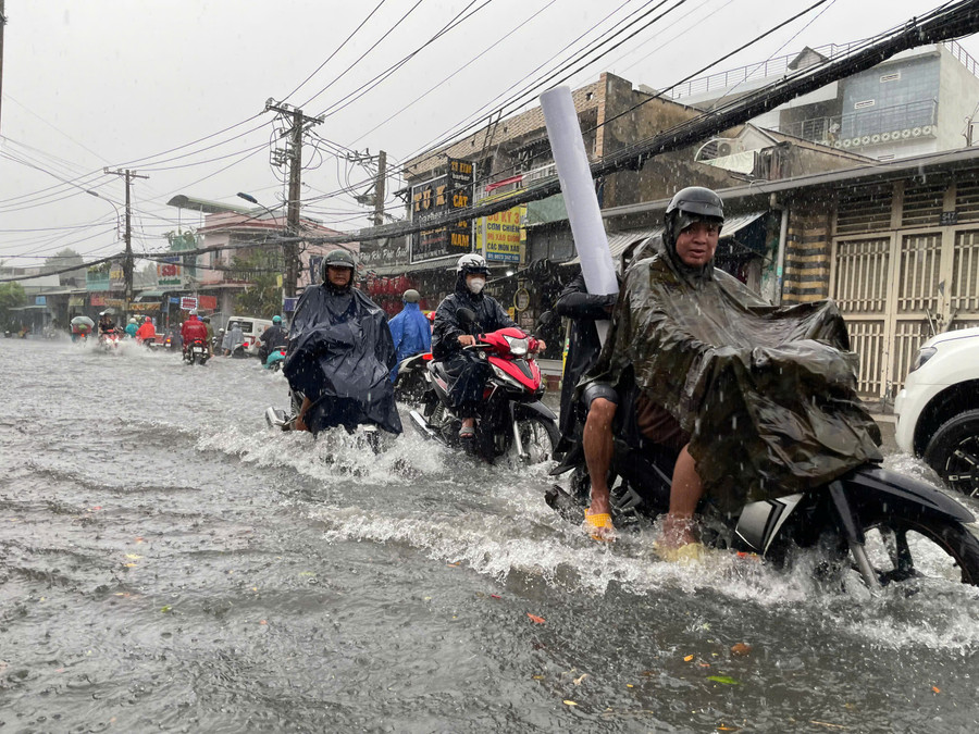 Đường Tô Ngọc Vân từ 16h trong cơn mưa nặng hạt đã biến thành "sông" khiến người dân vất vả di chuyển khi nước ngập quá nửa bánh xe.