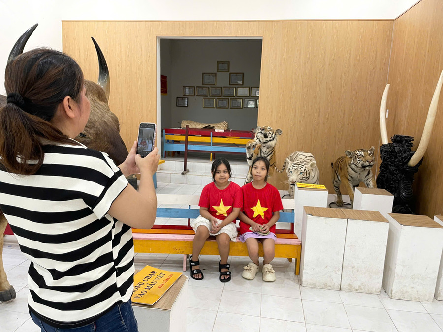 Hai em nhỏ mang áo Quốc kỳ Việt Nam được mẹ chụp hình lưu niệm khi tham quan bảo tàng động vật bên trong Thảo Cầm Viên. 4f0fc8b2f0bf7be122ae.jpg