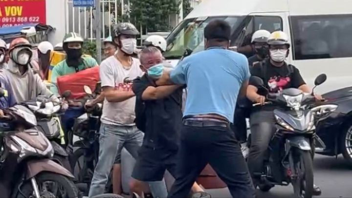 Tuấn (áo xanh) hành hung ông lão lớn tuổi tại giao lộ trung tâm TPHCM. (Ảnh: Cắt từ clip). danh-cu-ong-giua-o-phuong-sai-gon-nguoi-dan-ong-bi-cong-an-dua-ve-tru-so-2-1396-1103jpg.jpg