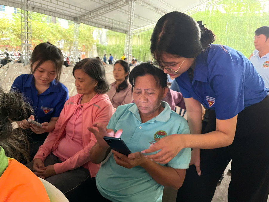 Đoàn viên thanh niên hướng dẫn người cao tuổi sử dụng các ứng dụng hành chính công trên điện thoại tại sự kiện. Ảnh: Hà An.