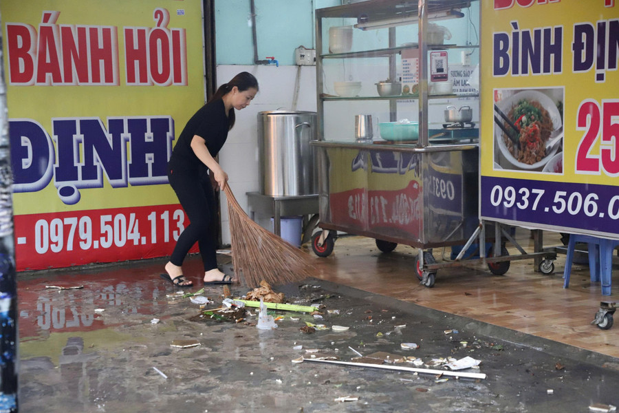 Người dân dọn rác dạt vào nhà vì đường ngập. ad7635ff6b0fe351ba1e.jpg