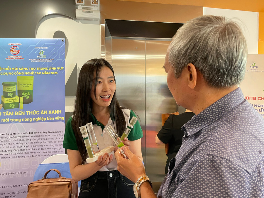 Phạm Ngọc Hà, học viên cao học tại Trường Đại học Đà Lạt giới thiệu khách tham quan sản phẩm thức ăn dinh dưỡng từ bèo tấm. Ảnh: Hà An.