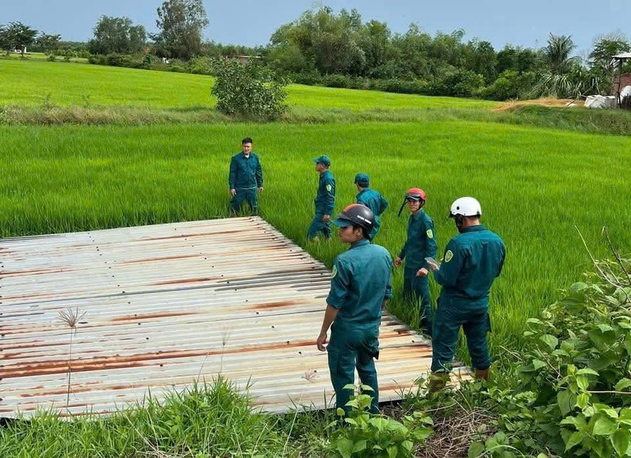 Lực lượng chức năng xử lý mái nhà dân bị tốc nằm rạp trên ruộng lúa. (Ảnh: Phúc Uyên) 9a7cb5599904105a4915.jpg
