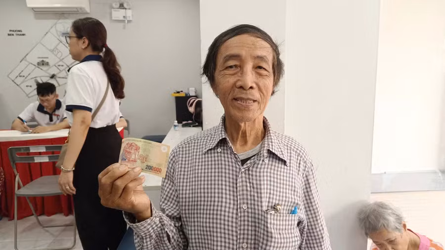 Ông Lương Văn Nông nhận quà tặng 200.000 đồng cho 2 vợ chồng ông từ điểm chi trả của UBND phường Bến Thành. Ảnh: Phúc Uyên.