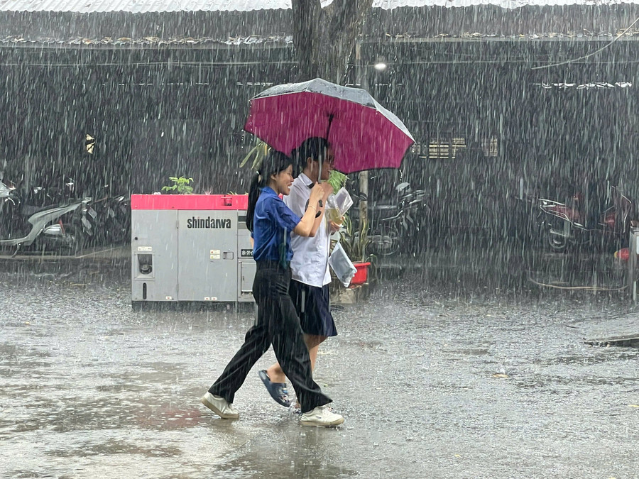 Thí sinh được tình nguyện viên che ô rời khỏi trường thi sau khi kết thúc môn Ngữ văn. dc51b1f8ae25197b4034.jpg