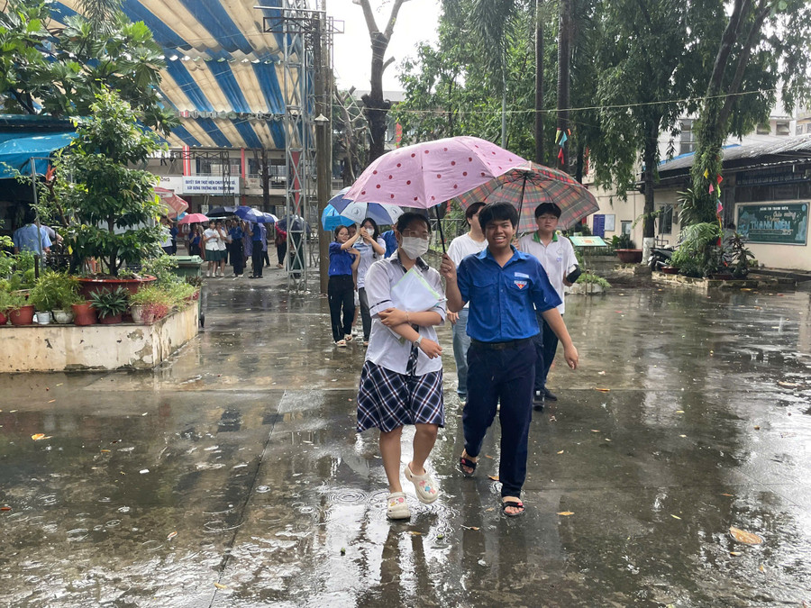 Do sau khi thi xong trời đổ mưa, nên thí sinh được tình nguyện viên che ô ra khỏi trường tại điểm thi Trường THPT Dĩ An. f46add8a38518f0fd640.jpg