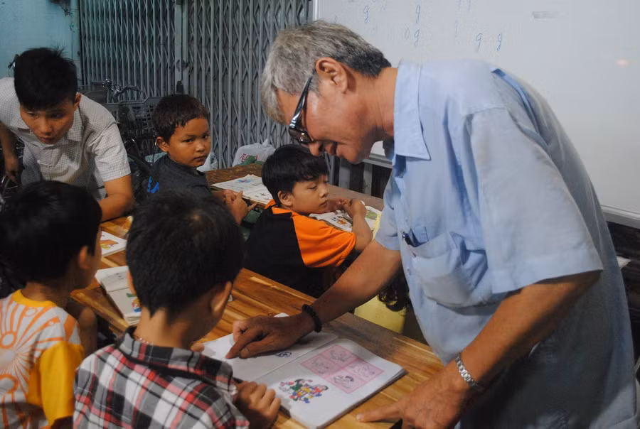 Ông Đoàn Minh Hùng chỉ bài cho học sinh tại lớp học tình thương. Ảnh: Phúc Uyên.