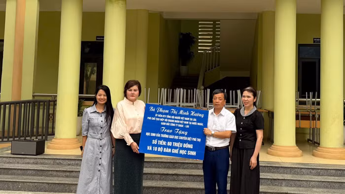 Bà Phạm Thị Minh Hường (thứ 2 từ trái qua) trao tặng tiền và bàn ghế cho nhà trường.