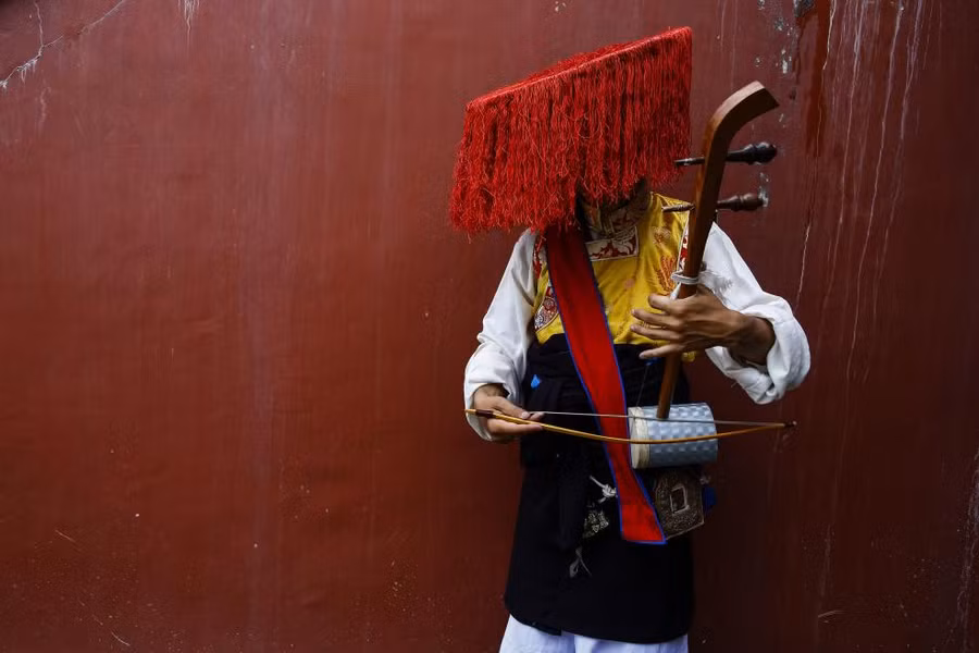 Một nghệ sĩ Tây Tạng chơi nhạc cụ trước lễ kỷ niệm sinh nhật lần thứ 82 của Dalai Lama ở Kathmandu, Nepal