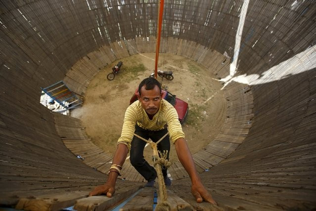Một người đàn ông trèo lên để kiểm tra các mấu chốt trước khi tay đua bắt đầu tiết mục. Nếu bề mặt những thanh gỗ không bằng phẳng, nó có thể gây ảnh hưởng, thậm chí là tai nạn, cho tài xế. e
