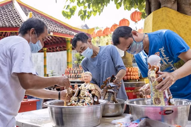 Những người đàn ông Bali lau tượng chuẩn bị cho Tết Nguyên đán tại một ngôi đền ở Kuta, Bali, Indonesia.