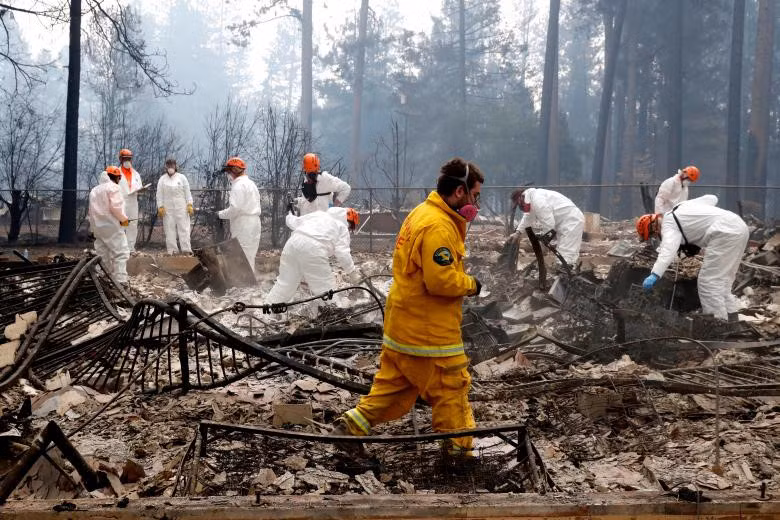 "Hãy tìm hộp sọ, những mảnh xương lớn", một nhân viên pháp y nói với những người khác trong khi tìm kiếm thi hài các nạn nhân. 5 ngày sau khi ngọn lửa bắt đầu, hôm 13/11, lực lượng lính cứu hỏa, điều tra viên và nhân viên giám định pháp y vẫn đang nỗ lực dập lửa tại tại một số vùng, đồng thời tiếp tục công cuộc cứu hộ cứu nạn. Ảnh: Reuters.